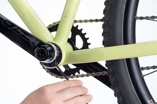 A mechanic installs a Bushnell Eccentric Bottom Bracket into a bike frame.